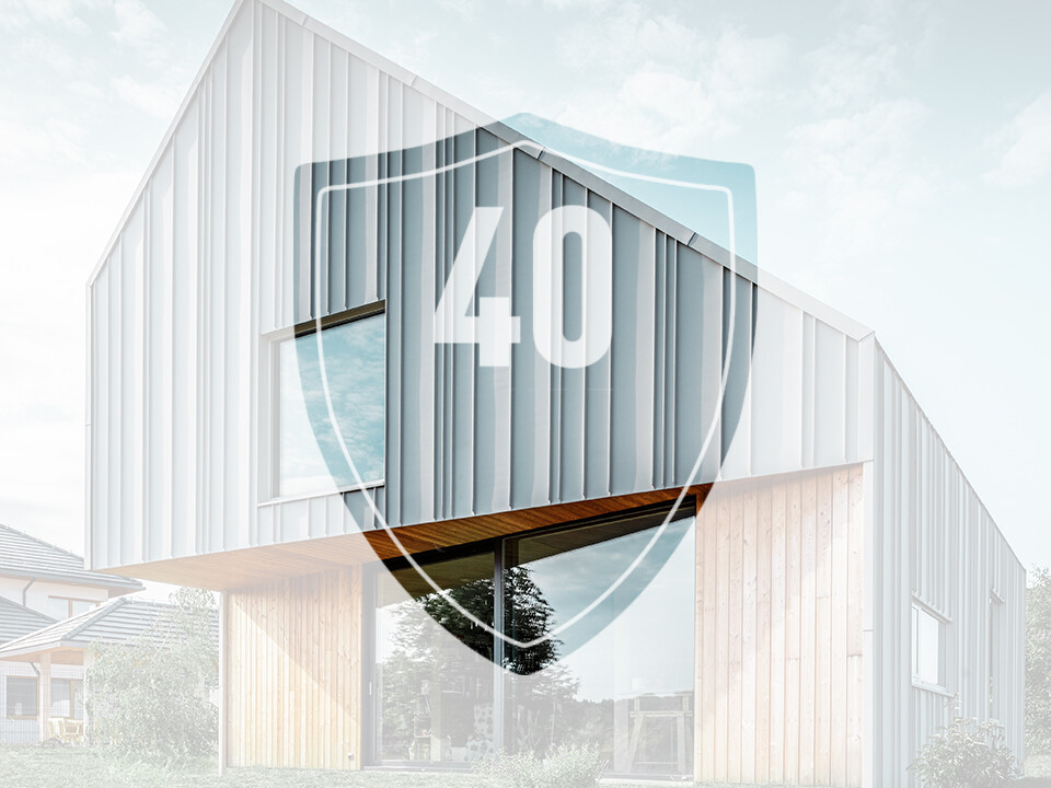 Na sliki je znak s številko „40“, ki naj bi predstavljal garancijo za aluminijaste izdelke PREFA, pred sodobno enodružinsko hišo.
