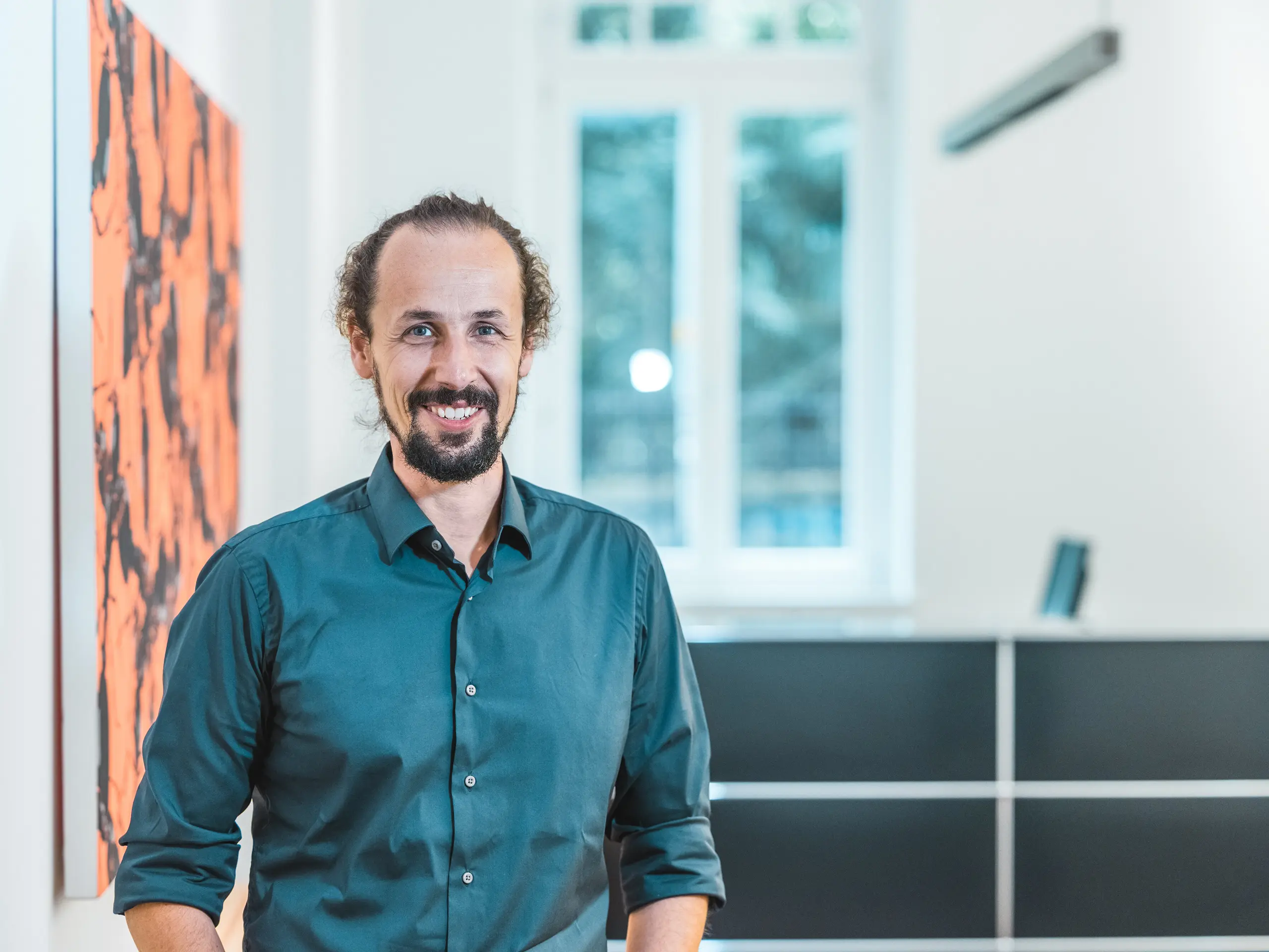 Portret arhitekta Gianfranca Berardesce v sodobno zasnovanem notranjem prostoru. Kot vodja projekta pri arhitekturnem biroju Höller & Klotzner Architekten je sodeloval pri izvedbi izobraževalnega centra Riffian na Južnem Tirolskem. Nagrajeni referenčni objekt PREFA, prekrit s strešnimi rombi PREFA 44 × 44 v barvi P.10 bronasta, je odličen primer natančnega načrtovanja, kakovostne arhitekture in vrhunskega južnotirolskega obrtniškega znanja.