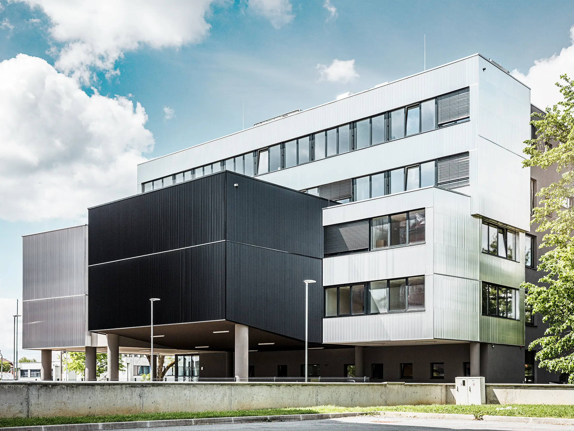 Stranski pogled na glasbeno šolo v Bjevolarju z moderno PREFA fasado z zobčastim profilom. Fasada je v črni in naravni aluminijasti barvi, geometrične oblike pa ustvarjajo izrazit, minimalističen dizajn.