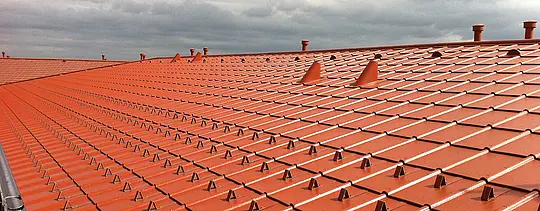 Nahaufnahme eines PRStreha PREFA iz aluminija v videzu opeke - strešna plošča PREFA v opečnato rdeči barvi s snegoloviEFA Daches aus Aluminium in Ziegeloptik - PREFA Dachplatte in Ziegelrot mit Schneestoppern