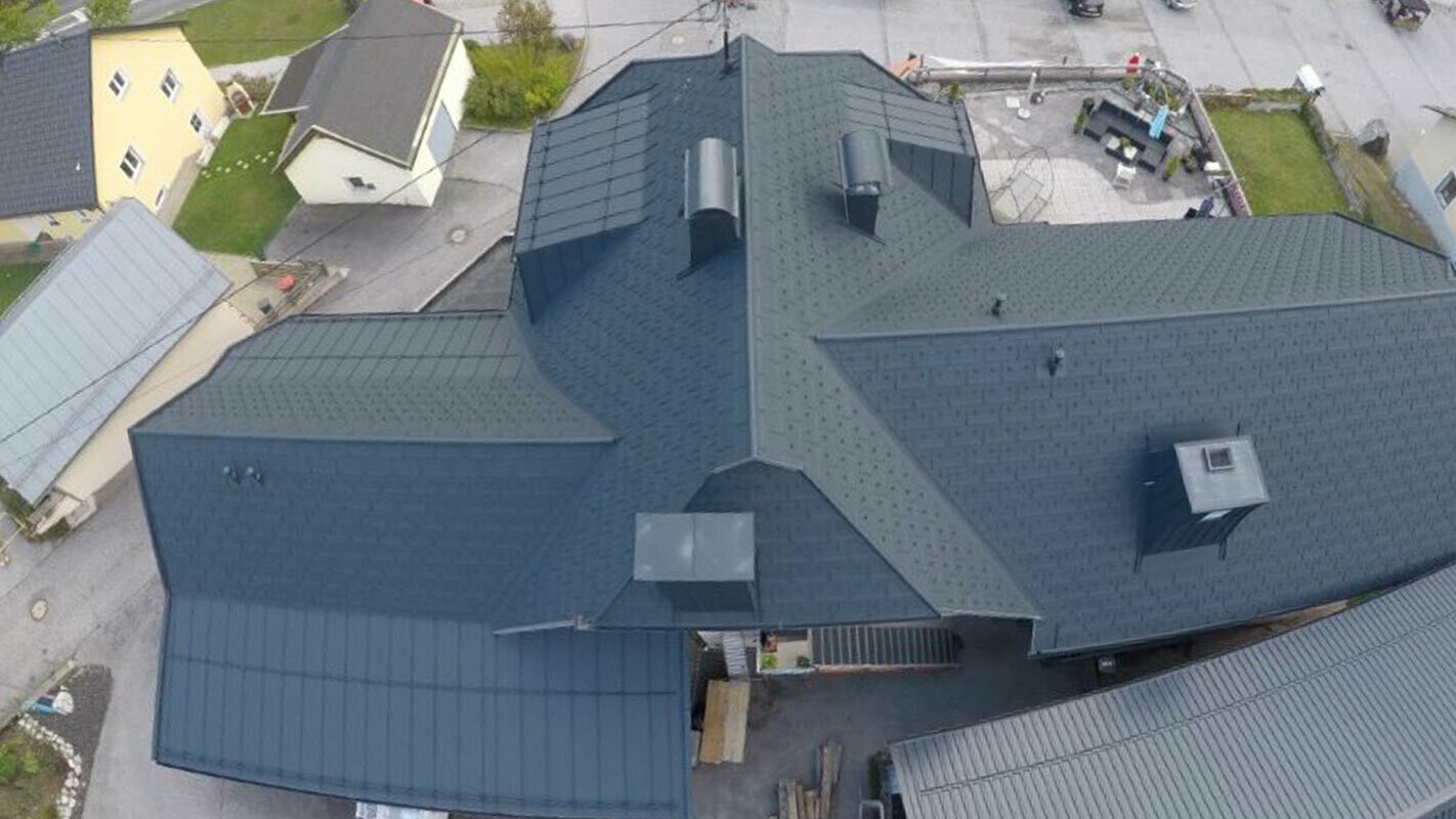 Obnova velike strešne površine s številnimi podrobnostmi – žlotami, mansardnimi okni in dimniki. Streha je prekrita z aluminijastimi strešnimi ploščami PREFA R.16 v antracitni barvi.