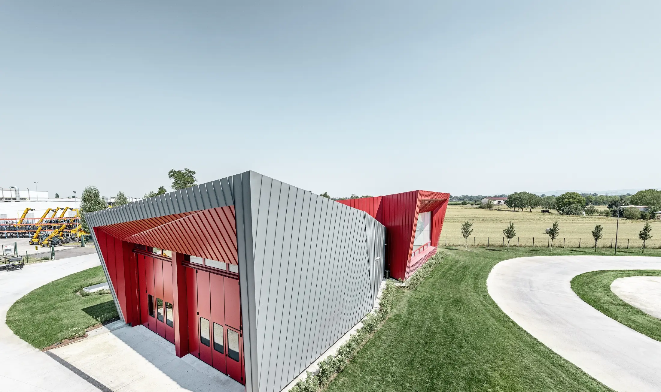 Sodobno izobraževalno središče Dieci v kraju Montecchio Emilia v Italiji s tribuno z aluminijasto fasado Prefalz v svetlo sivi barvi in sistemom Falzonal v kaminsko rdeči barvi