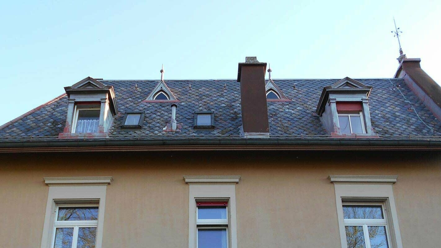 Stara streha z igrivimi mansardnimi okni pred obnovo s strešnimi rombi PREFA