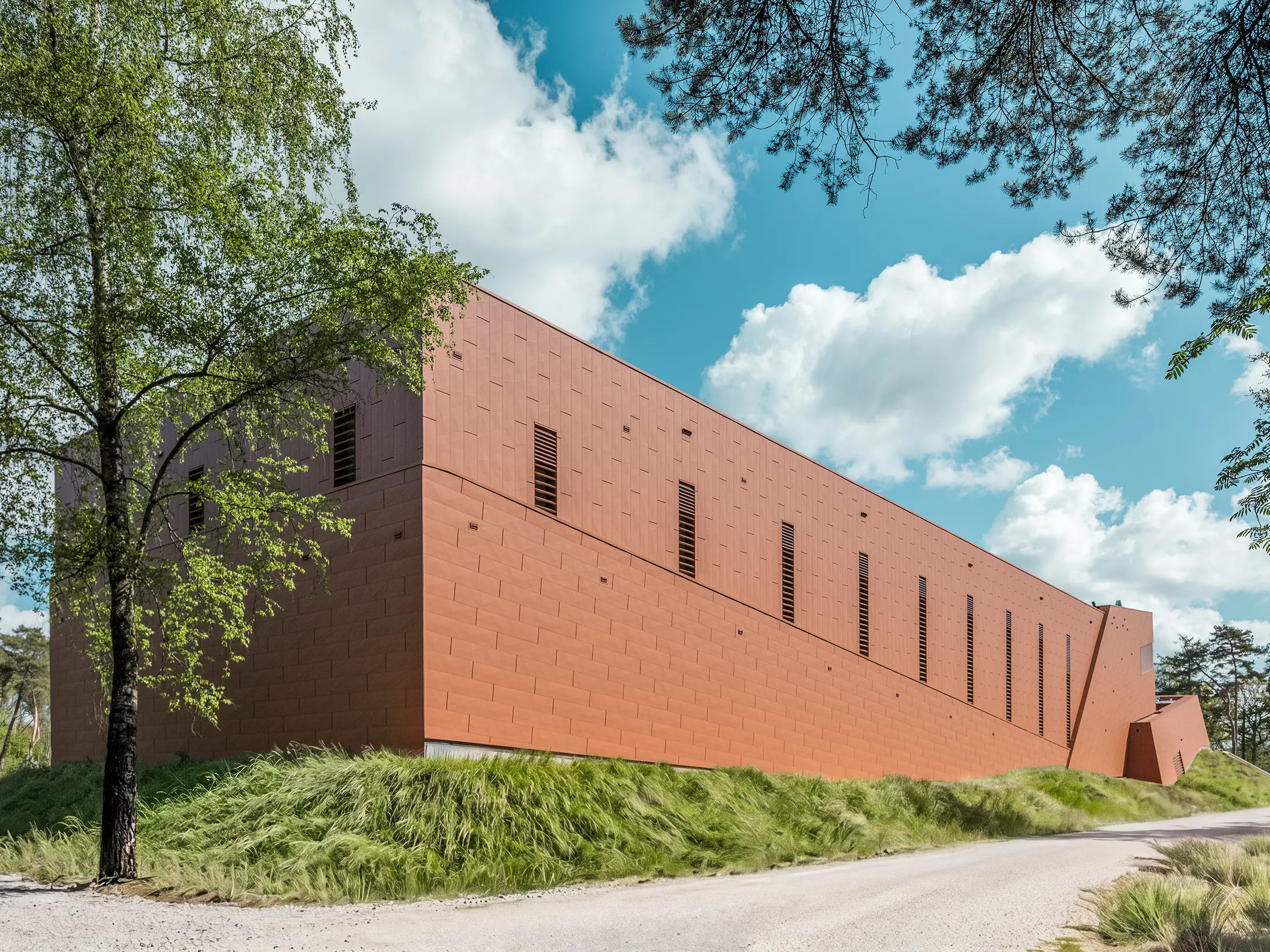 Podolgovata črpalna postaja za pitno vodo WML v Lottumu se kaže kot mogočna stavba sredi naravne pokrajine z drevesi, travniki in panoramskim razgledom na nebo. Izrazita aluminijasta fasada PREFA Siding.X v topli rjavi barvi kot vizualna atrakcija pritegne vse poglede in navdušuje s svojo fino fasetirano, živahno strukturirano površino. Tanke, navpične odprtine ritmično razčlenjujejo fasado. Trajni, lahki in reciklirani PREFA aluminijasti paneli zagotavljajo najvišjo odpornost proti vremenskim vplivom, barvno obstojnost ter trajnostno, vzdrževanju prijazno ovojnico stavbe.