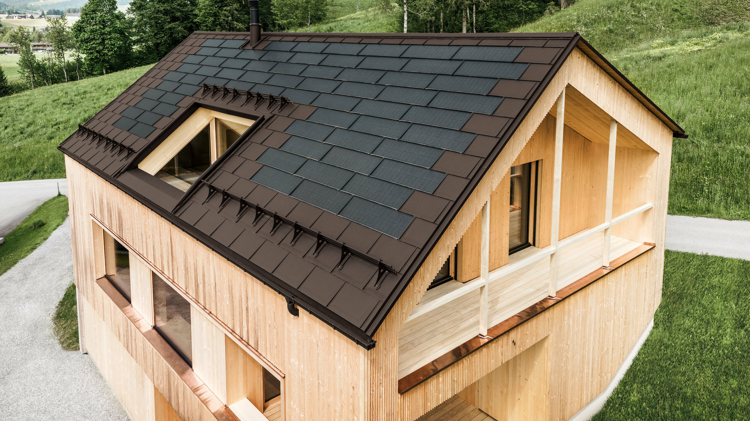 Einfamilienhaus im österreichischen Ort Egg mit der PREFA Solardachplatte und der Dachplatte R.16 in Nussbraun, kombiniert mit einer Holzfassade