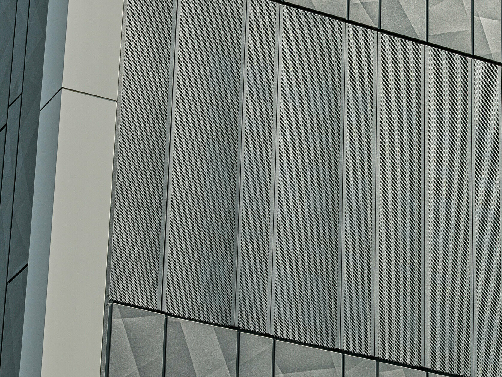 Pogled na fasado trgovine Eurospar v Rohrbachu s PREFA Siding.X in perforiranimi oblogami v barvi antracitna. Elementi Siding.X kažejo živahen, geometričen vzorec fug, medtem ko perforirane obloge ponujajo moderno, zračno strukturo.