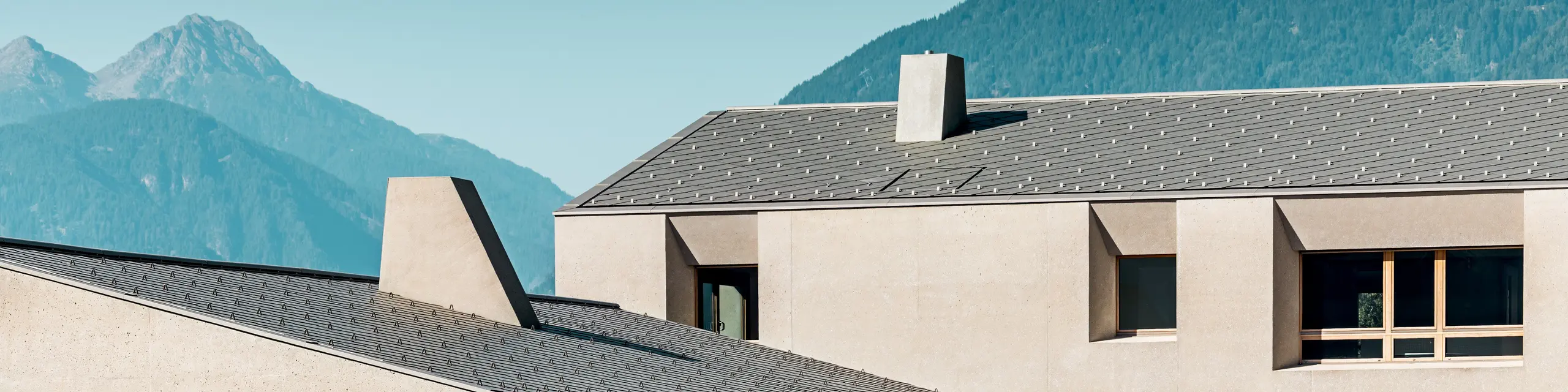 Izobraževalni center Riffian na Južnem Tirolskem izstopa s strešnimi rombi PREFA 44 × 44 v barvi P.10 bronasta, ki ustvarjajo izrazit poudarek v alpskem okolju. Natančno položena aluminijasta strešna kritina se harmonično dopolnjuje z umirjeno fasado, katere površina spominja na glineni omet, ter poudarja sodobno arhitekturo vrtca in osnovne šole.