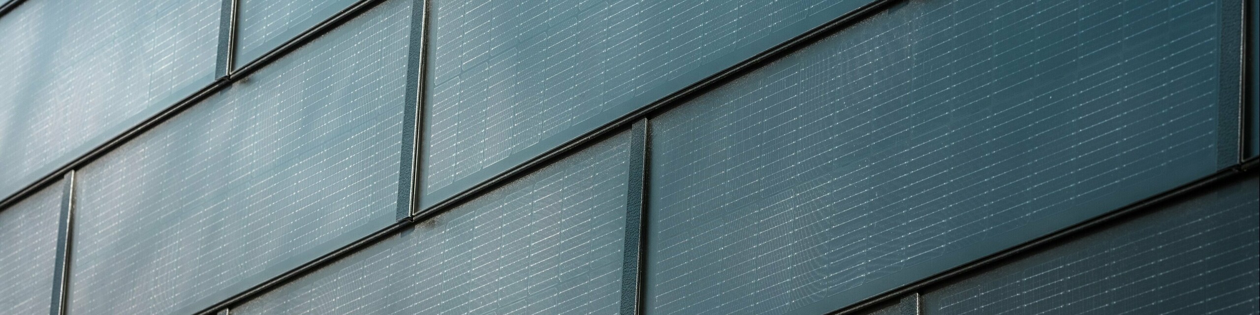 Bližnji posnetek fasade s solarnimi strešnimi ploščami PREFA: fotonapetostni moduli, vgrajeni v fasadni sistem, proizvajajo trajnostno električno energijo in zagotavljajo sodoben, estetski videz.