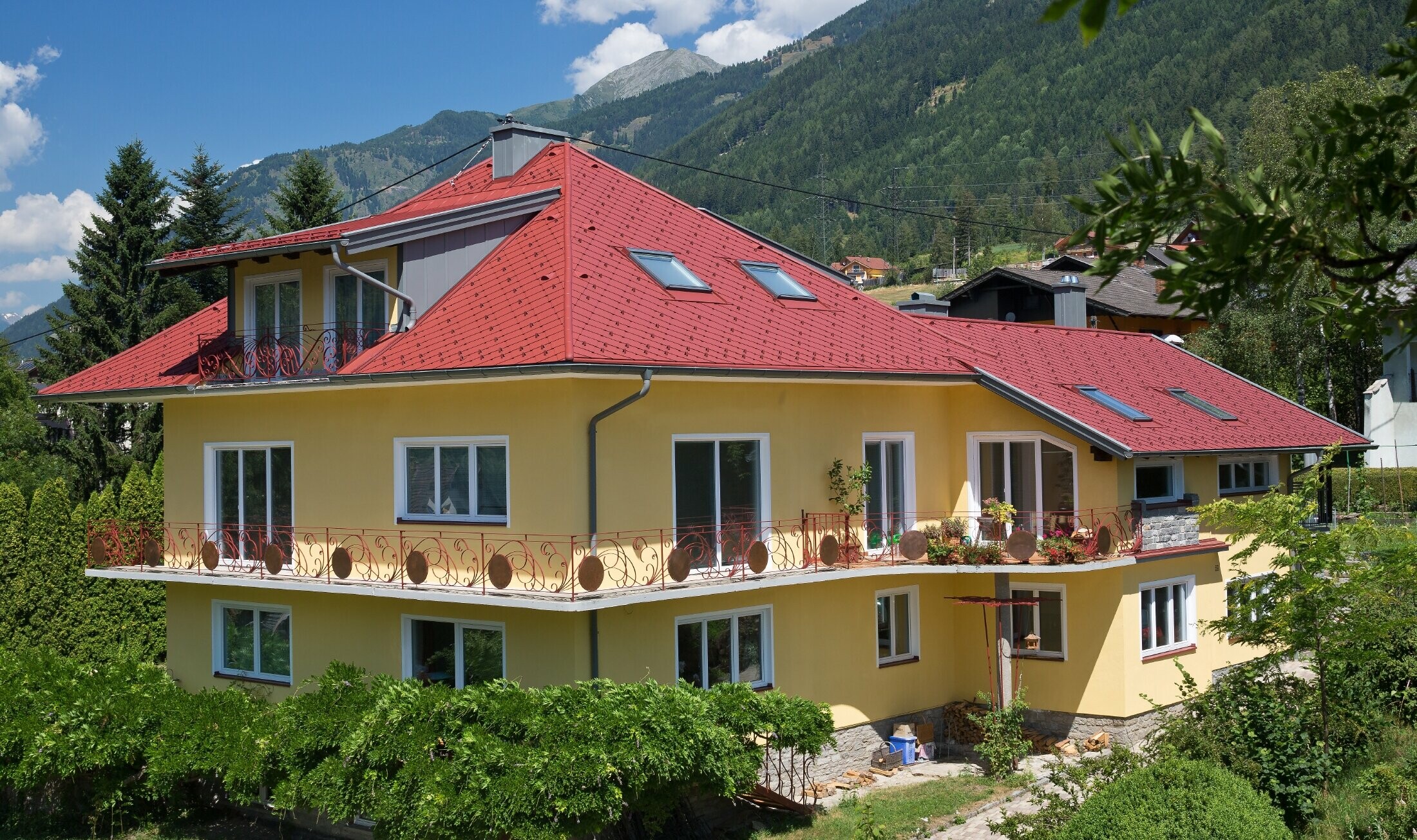 klasična enodružinska hiša s čopasto streho, prekrita s strešnimi rombi v oksidno rdeči barvi.