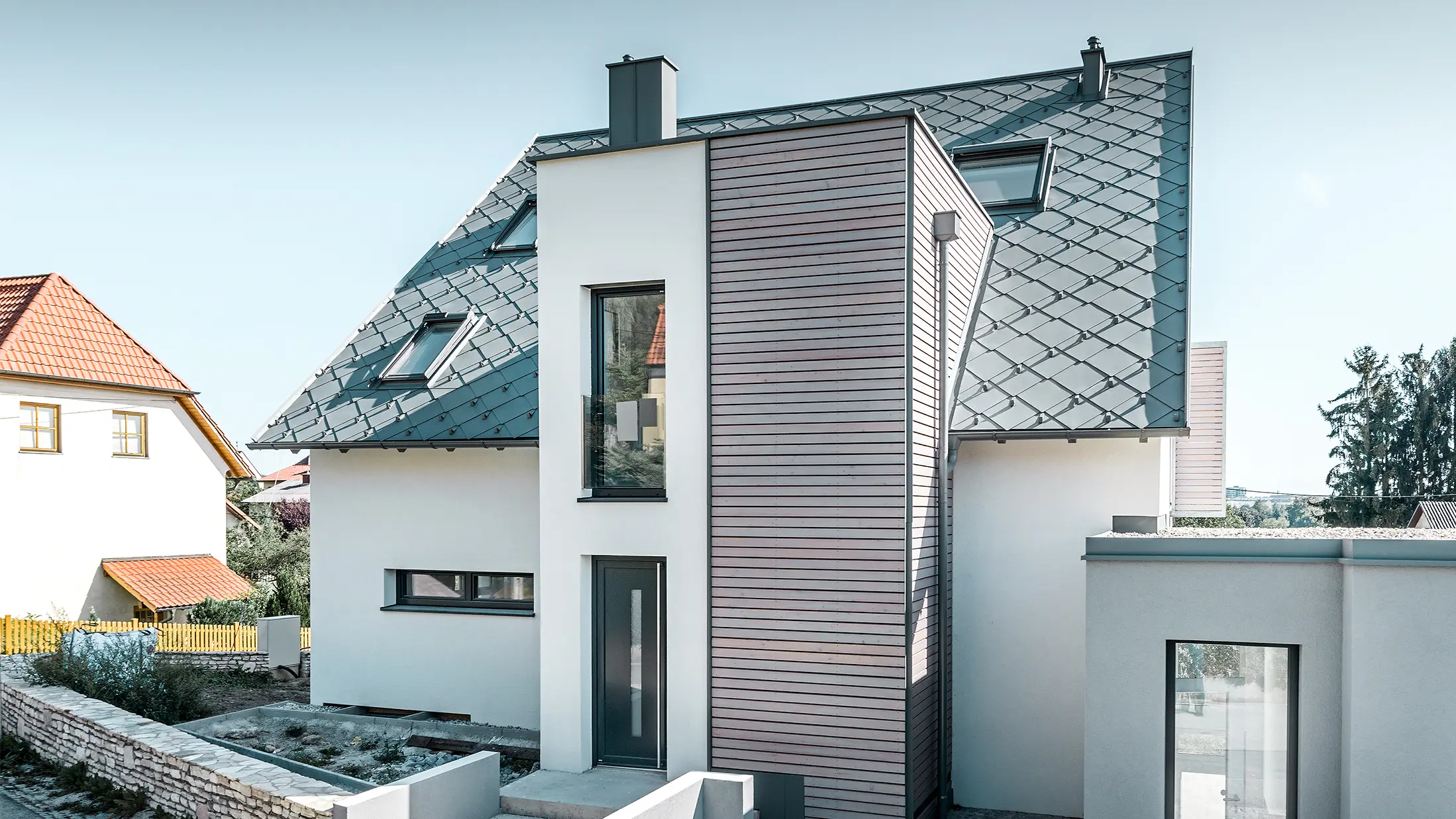 Das Einfamilienhaus mit Satteldach in Leodonding wurde rundum saniert. Die Dachfläche wurde neu mit der PREFA Dachraute 44 × 44 in Hellgrau inklusive Schneestoppern eingedeckt. Die Rinne ist die Hängerinne von PREFA, ebenfalls in Hellgrau. 