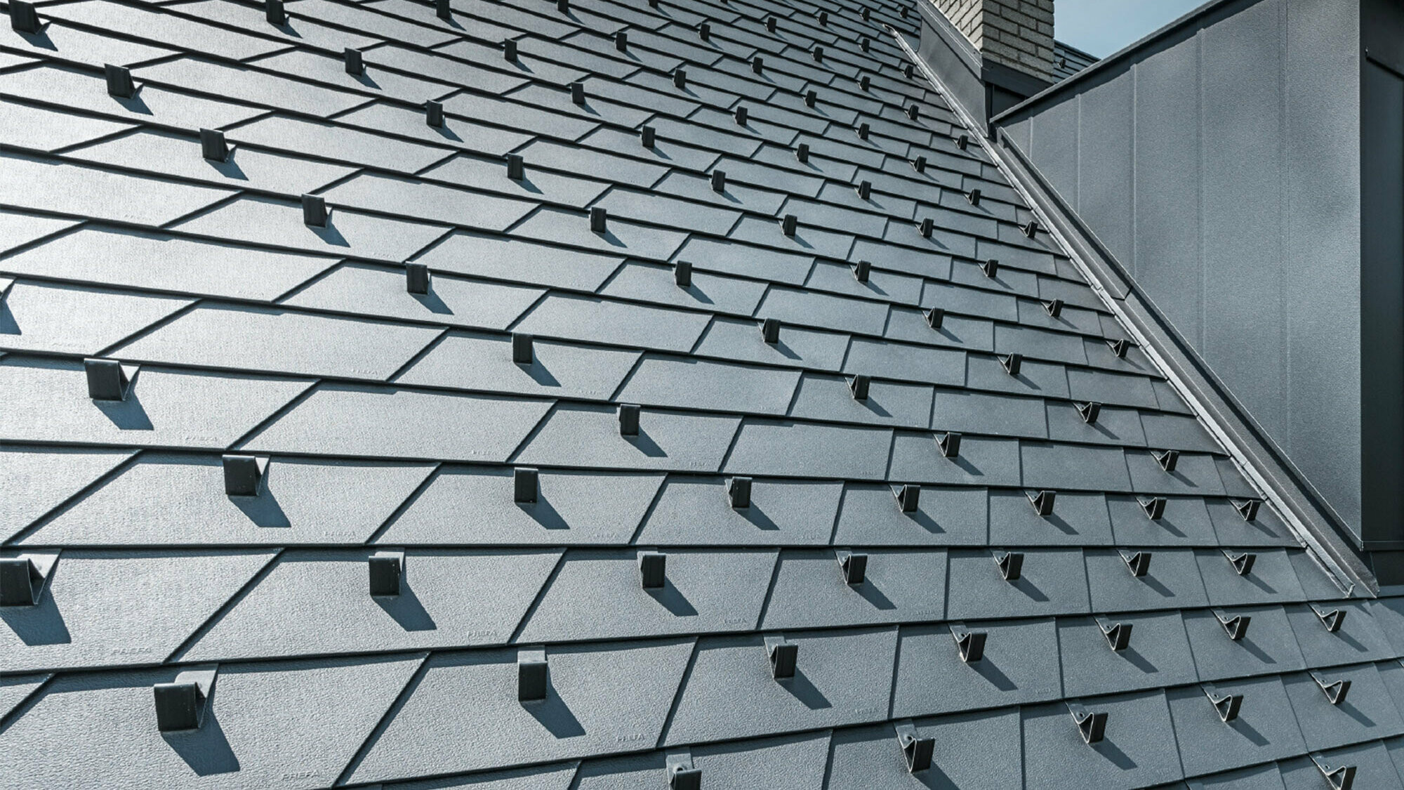 Prenovljena streha s strešnimi skodlami PREFA v izvedbi P.10 črna, vključno s snegolovom, frčada je prekrita z aluminijem PREFA