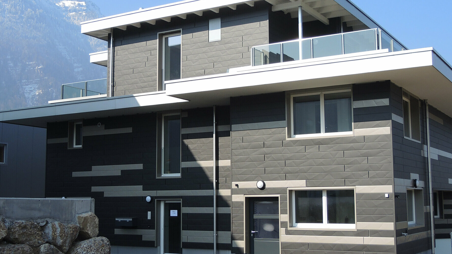 Ustvarjalno oblikovana fasada z novimi fasadnimi paneli PREFA Siding.X v dveh različnih barvah.