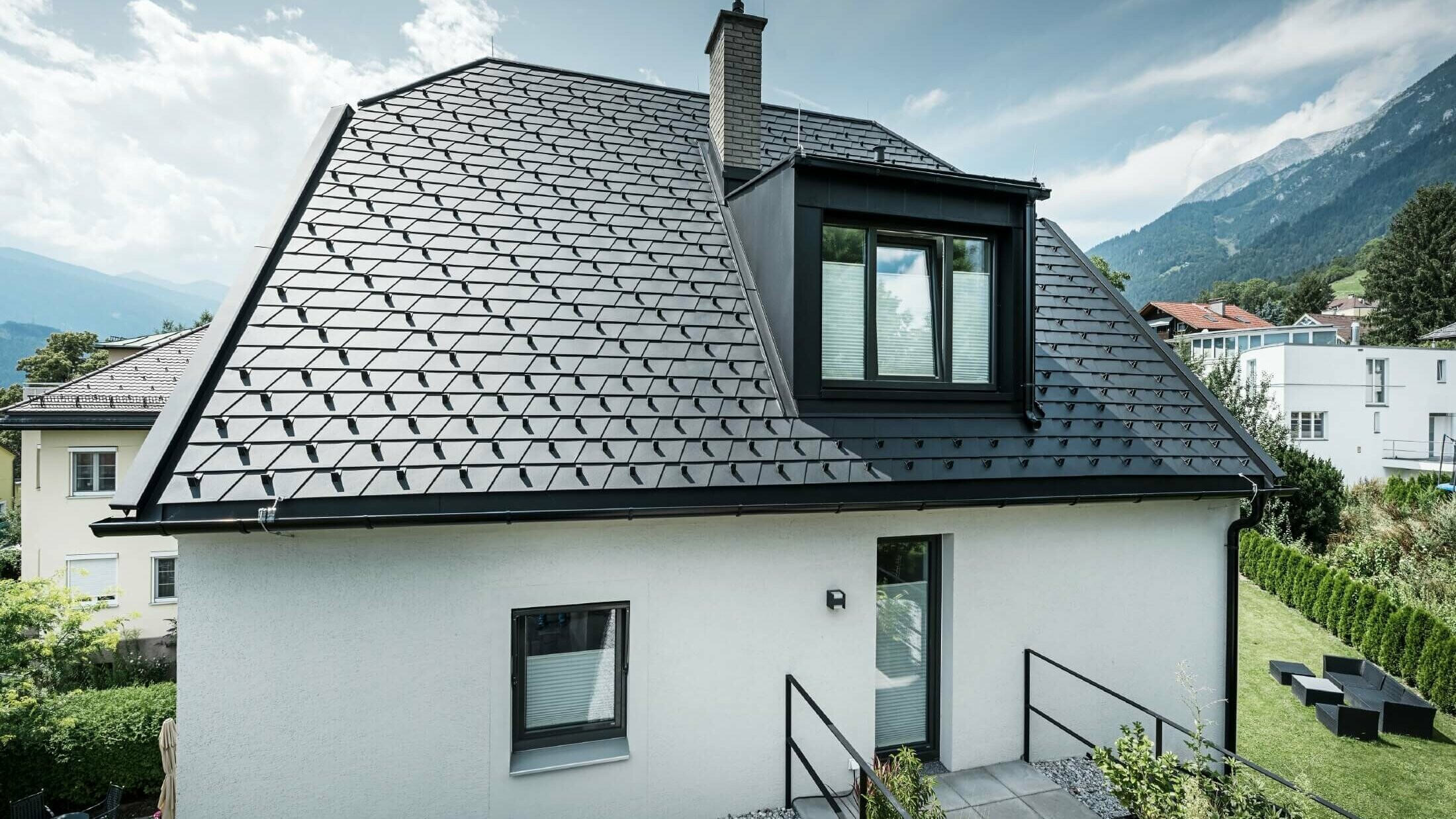 Majhna družinska hiša z mansardnim oknom. Streha je bila prekrita s strešnimi skodlami PREFA v barvi P.10 črna. 
