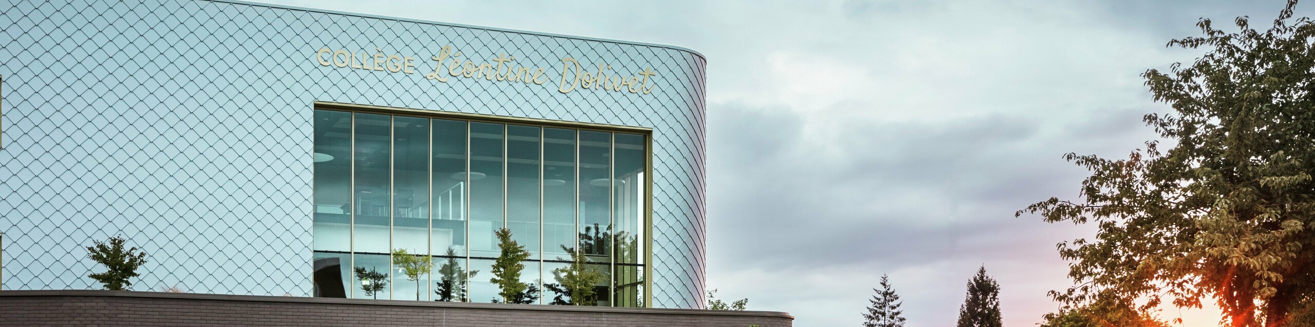  Moderna šolska stavba Collège Léontine Dolivet v Cesson-Sévigné z izrazito aluminijasto fasado iz okoli 15.000 PREFA fasadnih rombov v kovinsko srebrni barvi. Bleščeča površina odbija svetlobo in ustvarja živahen, eleganten videz. Velika steklena fasada odpira pogled na zelenje, robustna PREFA fasadna rešitev pa zagotavlja dolgo življenjsko dobo in odpornost proti vremenskim vplivom. Kombinacija spreminjajočega se kovinskega videza in jasne arhitekture naredi stavbo pravo pašo za oči in poudarja prednosti aluminija: lahkost, brez vzdrževanja in trajnost.