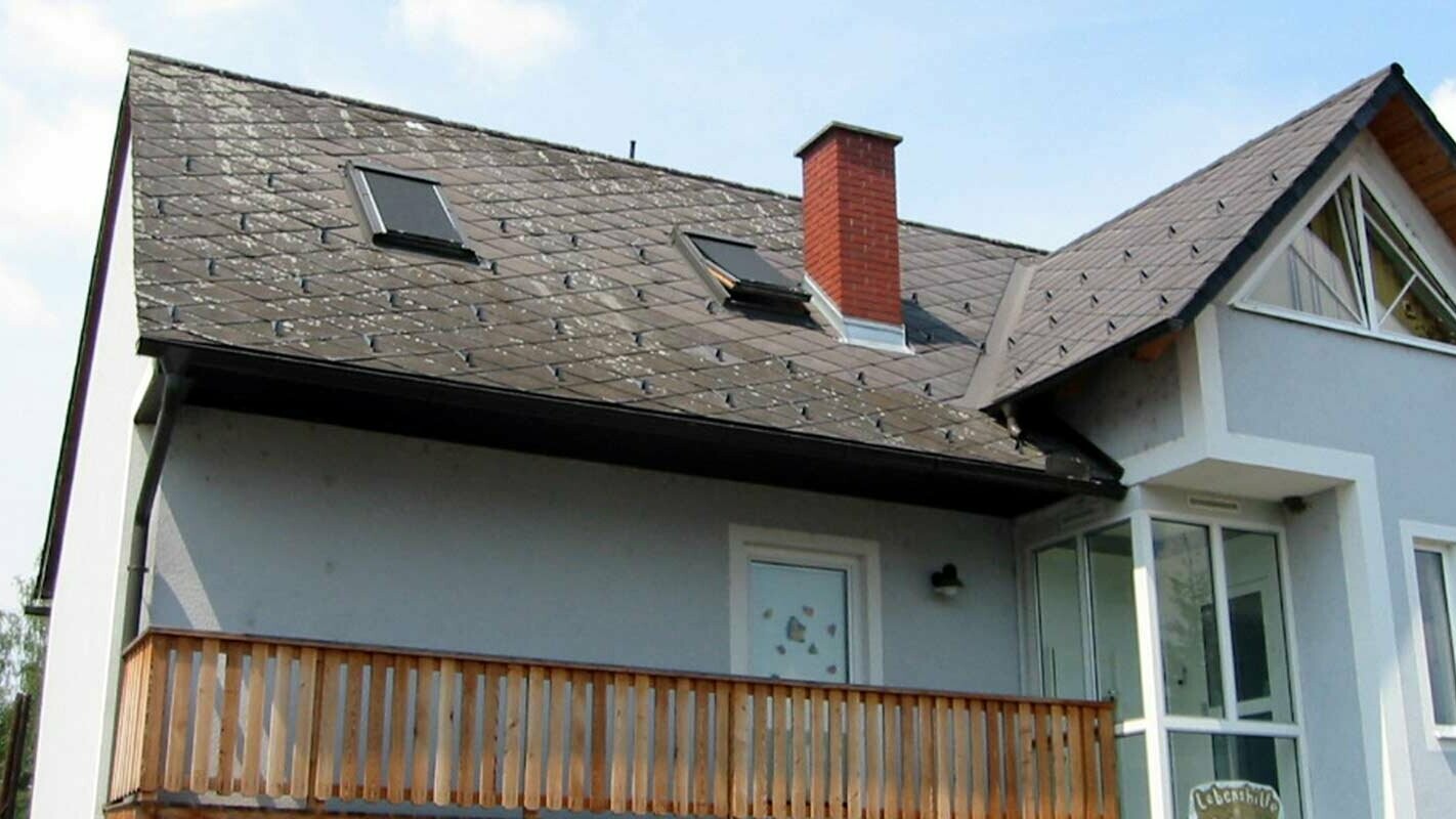 Enodružinska hiša z dvokapno streho, modro fasado in zidanim opečnatim dimnikom – stara streha je potrebna obnove