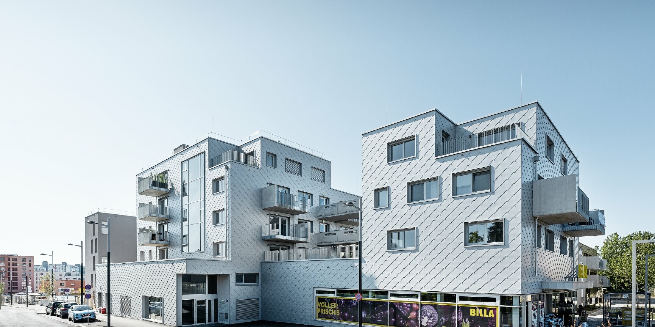 Stanovanjska naselja z ravnimi strehami in fasadnimi rombi 44 x 44 PREFA na fasadi v kovinsko srebrni barvi