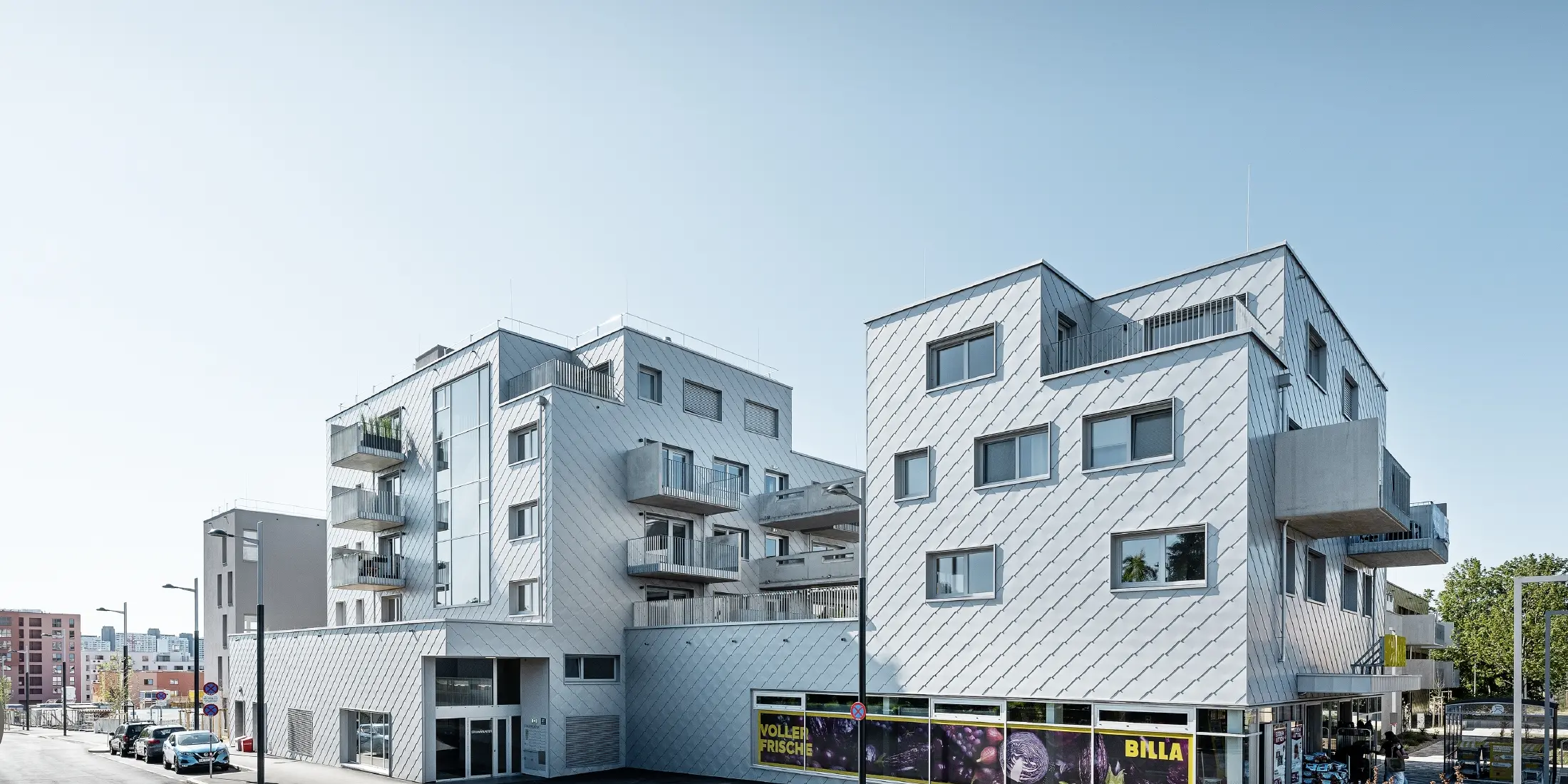 Stanovanjska naselja z ravnimi strehami in fasadnimi rombi 44 × 44 PREFA na fasadi v kovinsko srebrni barvi