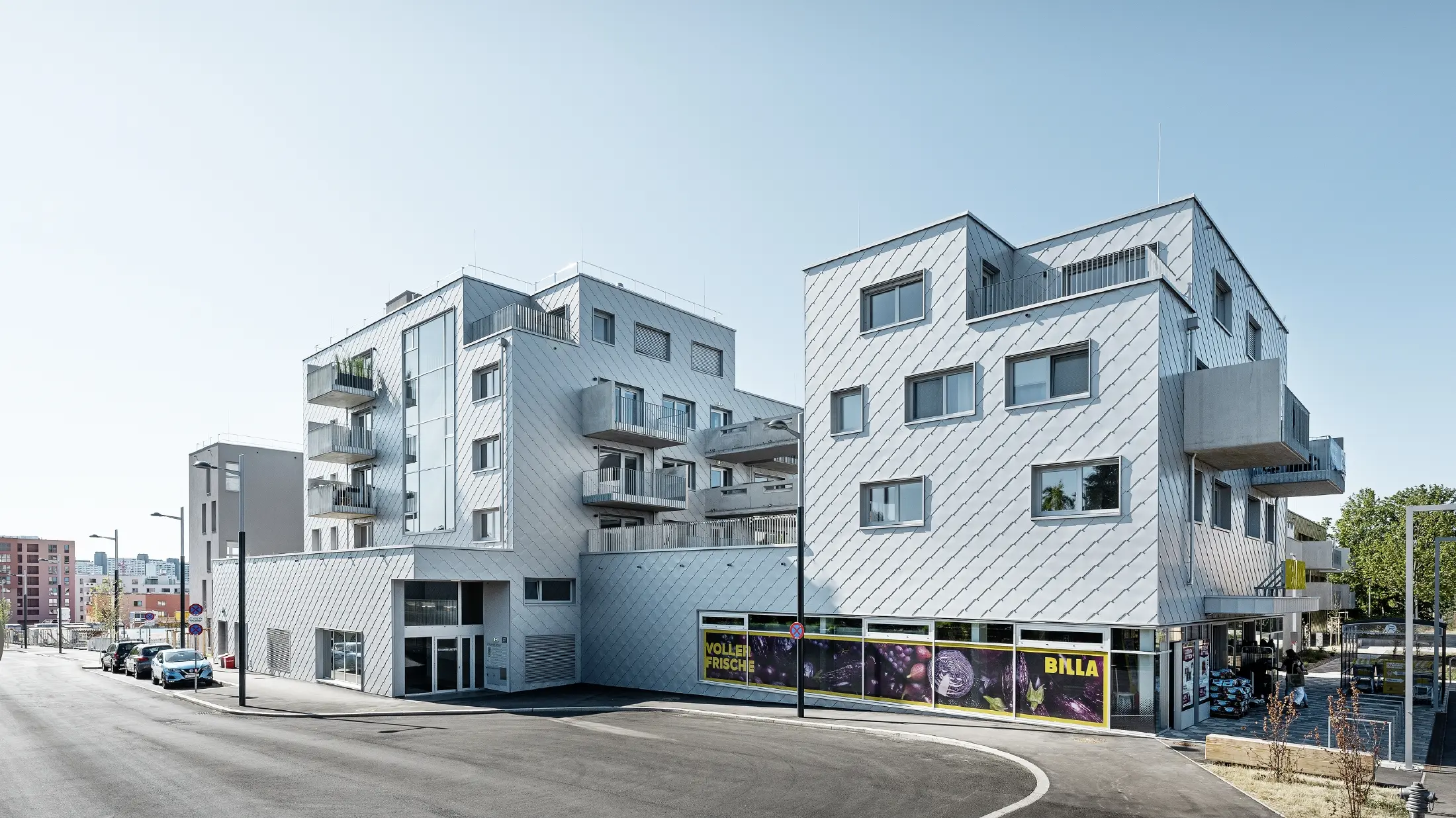 Stanovanjska naselja z ravnimi strehami in fasadnimi rombi 44 × 44 PREFA na fasadi v kovinsko srebrni barvi