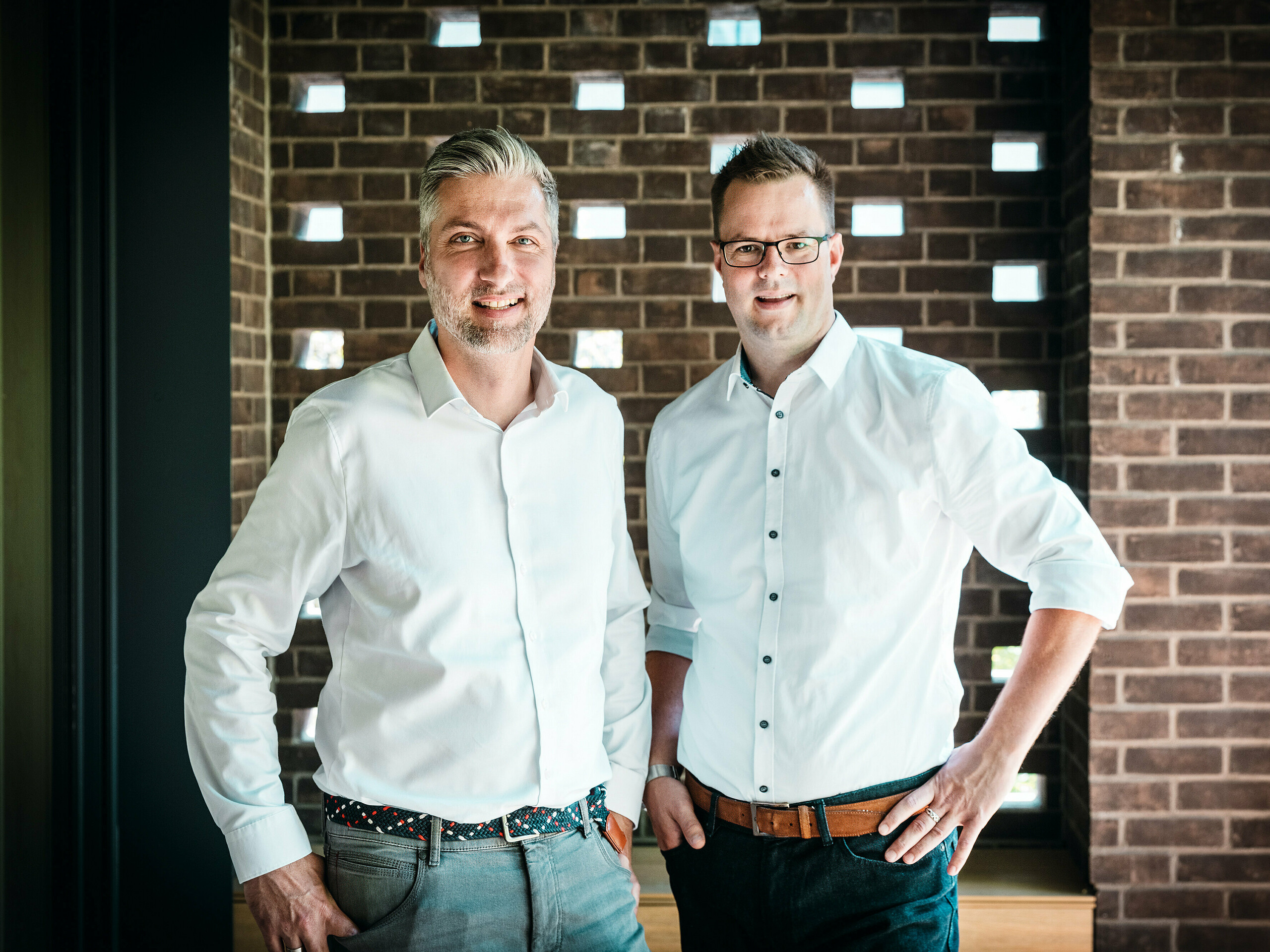 Arhitekturna ekipa A Fiúk Építész Stúdió stoji v sodobnem notranjem prostoru večgeneracijske vile v Budimpešti, ki je bila nagrajena v okviru PREFARENZEN 2026. Pred značilno opečno steno predstavljajo natančen jezik materialov in oblik svojega projekta, ki ga zaznamuje kubična PREFALZ-aluminijasta streha v barvi P.10 antracit. Prizor poudarja arhitekturno strokovnost, visokokakovostno izvedbo in premišljeno izbiro materialov, pri čemer PREFA aluminij prepriča s svojo trajnostjo, oblikovno močjo in tehnično natančnostjo.