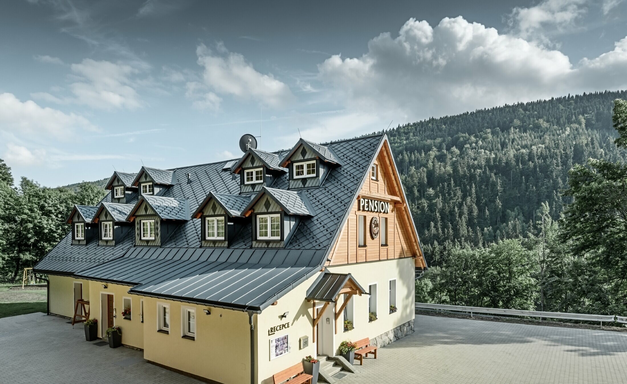 Penzion na Češkem s strmo streho in številnimi frčadami, prekrit z aluminijasto streho PREFA, streha z rombi v videzu lusk s snegolovi