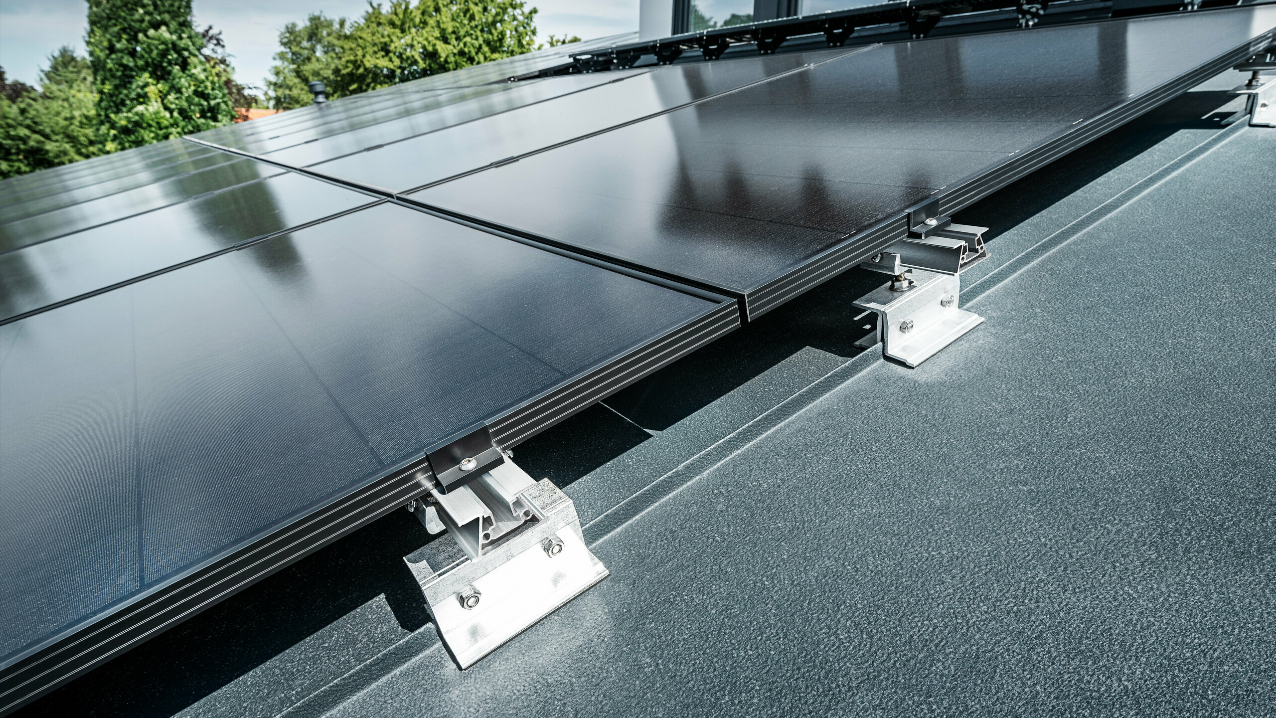 Bližnji posnetek PREFA solarnega nosilca PREFALZ Vario na strehi s stoječimi žlebovi v antracitni barvi