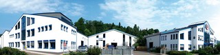Panoramaaufnahme des PREFA Standorts in Wasungen, Deutschland; weißes Gebäude mit blauen Fenstern