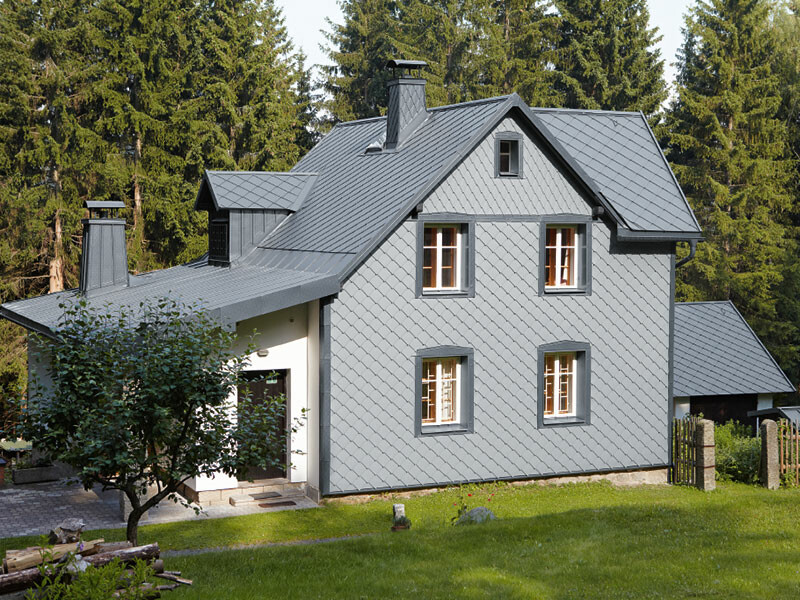 Enodružinska hiša ob gozdu z vremensko odporno aluminijasto fasado PREFA v svetlo sivi barvi.