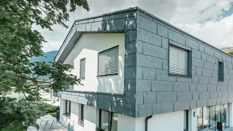 Prvo nadstropje sodobne stanovanjske stavbe obložene z aluminijastimi fasadnimi ploščami PREFA FX.12 v kamnito sivi barvi.