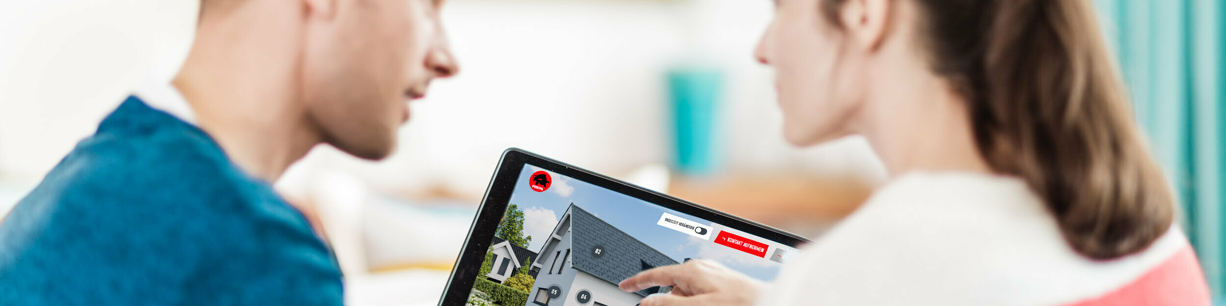 Ein Paar sitzt gemeinsam am Tisch und betrachtet auf einem Tablet die digitale Darstellung eines Hauses mit Dach, Fassade und Solar-Elementen aus Aluminium – im Kontext des PREFA Ratgebers zu Dach, Fassade und Solar für Hausbau und Sanierung.