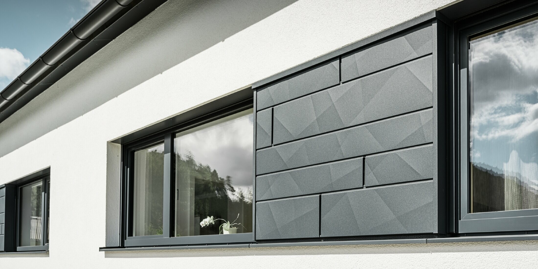 Detailansicht der Fenstereinfassung mit Siding.X Fassadenpaneelen in der Farbe P.10 Anthrazit.