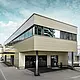 Moderen prizidek z delavnico in pisarno podjetja Guggisberg Dachtechnik z aluminijastimi kompozitnimi ploščami PREFA v bronasti barvi