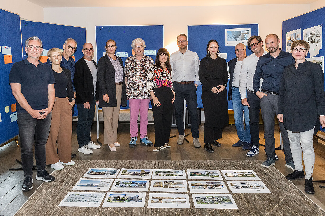 Skupinska fotografija žirije PREFARENZEN 2026 po uspešnem izbirnem postopku v vinogradniški rezidenci v Seewinklu na Gradiščanskem: Dirk Lorenz (Leinert Lorenz Architekten), Veronika Roll (marketing, PREFA Avstrija), Wolfgang Croce (Croce & Wir, Gradec), Jürgen Jungmair (vodja mednarodnega marketinga, PREFA), Judit Nemere (direktorica PREFA Madžarska), Matthias Finkentey (moderator), Bettina Almeida (upravljanje komunikacij, PREFA), Christian Wirth (regionalni vodja za vzhod, PREFA Avstrija), Selina Wach (vodja oddelka za diskurz, Architektur Aktuell), Thomas Schlett (B3 Architekten), Sven Disser (vodja razvoja, Bauwerk), Falk Leinert (Leinert Lorenz Architekten) in Juliane Croce (Croce & Wir, Gradec) stojijo pred končnimi arhitekturnimi projekti, izbranimi za arhitekturno knjigo PREFARENZEN in koledar 2026. Projekti odražajo raznolikost, trajnost in inovativno uporabo materialov PREFA.