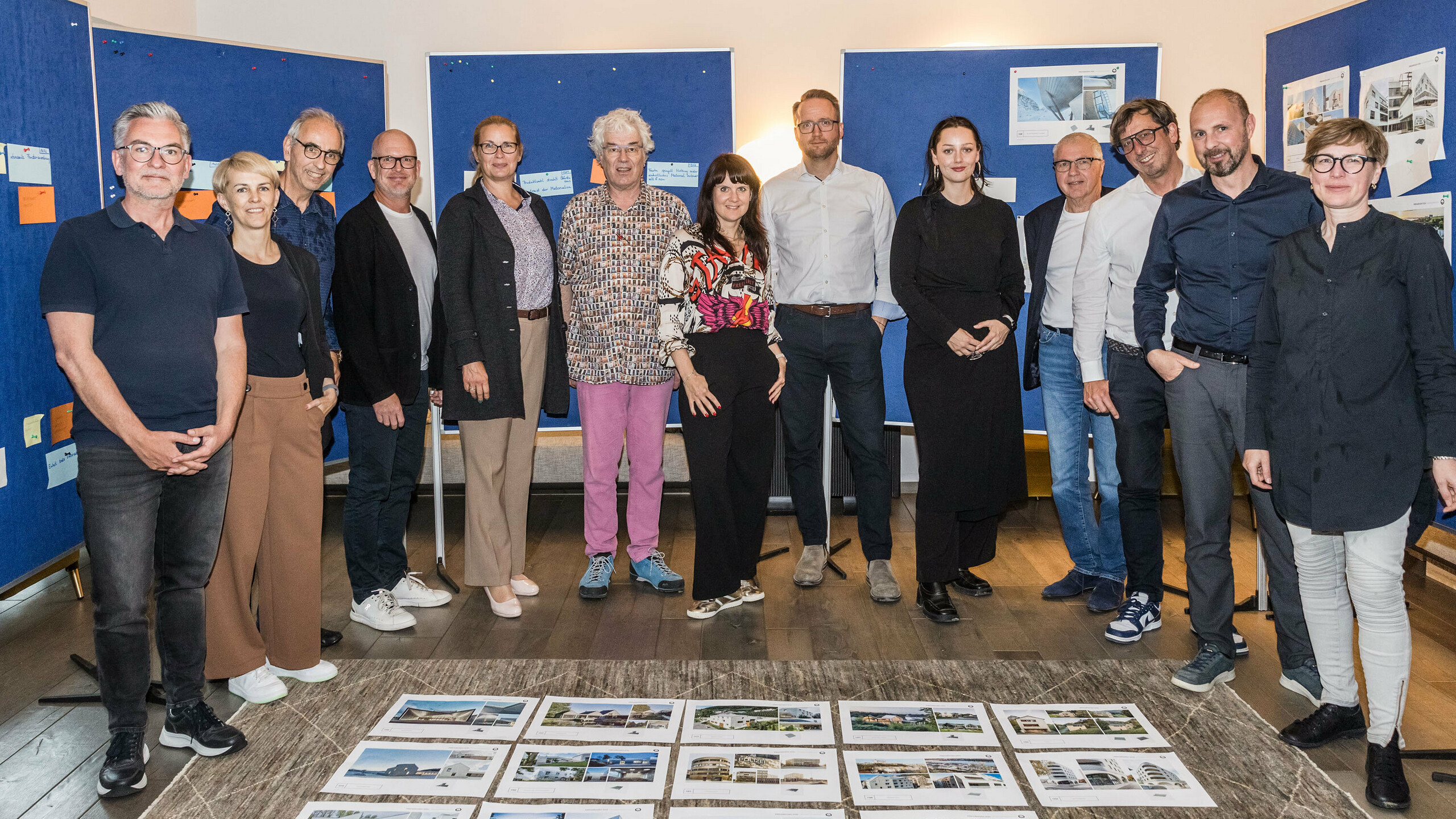 Skupinska fotografija žirije PREFARENZEN 2026 po uspešnem izbirnem postopku v vinogradniški rezidenci v Seewinklu na Gradiščanskem: Dirk Lorenz (Leinert Lorenz Architekten), Veronika Roll (marketing, PREFA Avstrija), Wolfgang Croce (Croce & Wir, Gradec), Jürgen Jungmair (vodja mednarodnega marketinga, PREFA), Judit Nemere (direktorica PREFA Madžarska), Matthias Finkentey (moderator), Bettina Almeida (upravljanje komunikacij, PREFA), Christian Wirth (regionalni vodja za vzhod, PREFA Avstrija), Selina Wach (vodja oddelka za diskurz, Architektur Aktuell), Thomas Schlett (B3 Architekten), Sven Disser (vodja razvoja, Bauwerk), Falk Leinert (Leinert Lorenz Architekten) in Juliane Croce (Croce & Wir, Gradec) stojijo pred končnimi arhitekturnimi projekti, izbranimi za arhitekturno knjigo PREFARENZEN in koledar 2026. Projekti odražajo raznolikost, trajnost in inovativno uporabo materialov PREFA.