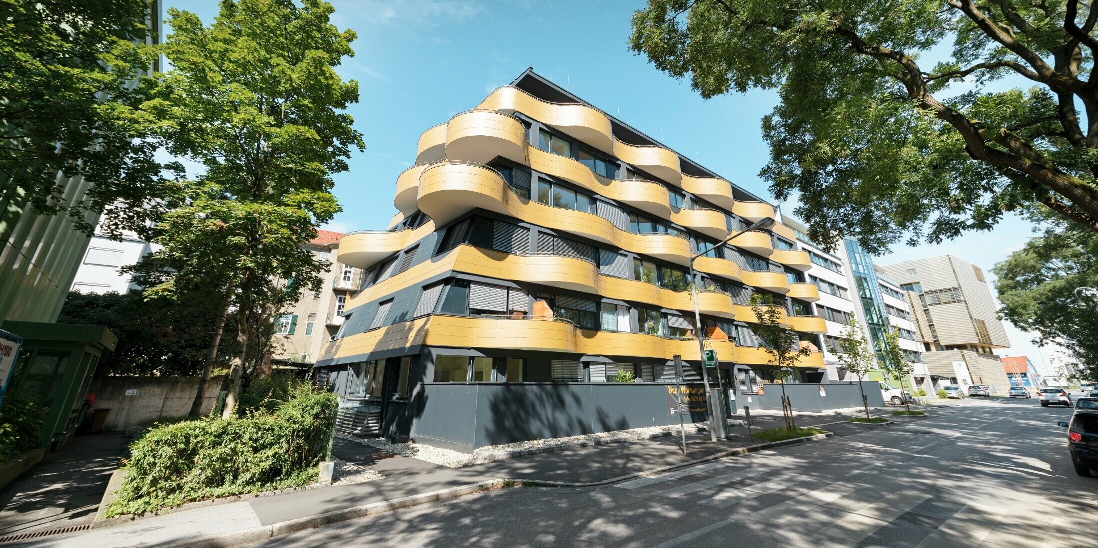 Stanovanjski kompleks »Goldene Welle« v Gradcu v Avstriji, z aluminijastimi kompozitnimi ploščami v zlati barvi, balkoni pa so zaobljeni v obliki valov 