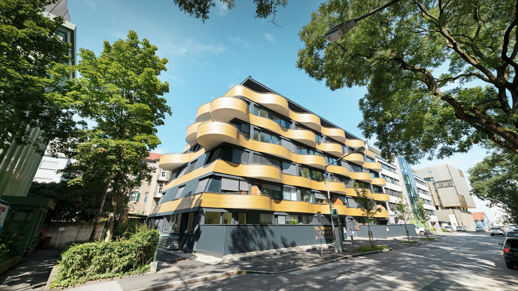 Stanovanjski kompleks »Goldene Welle« v Gradcu v Avstriji, z aluminijastimi kompozitnimi ploščami v zlati barvi, balkoni pa so zaobljeni v obliki valov 