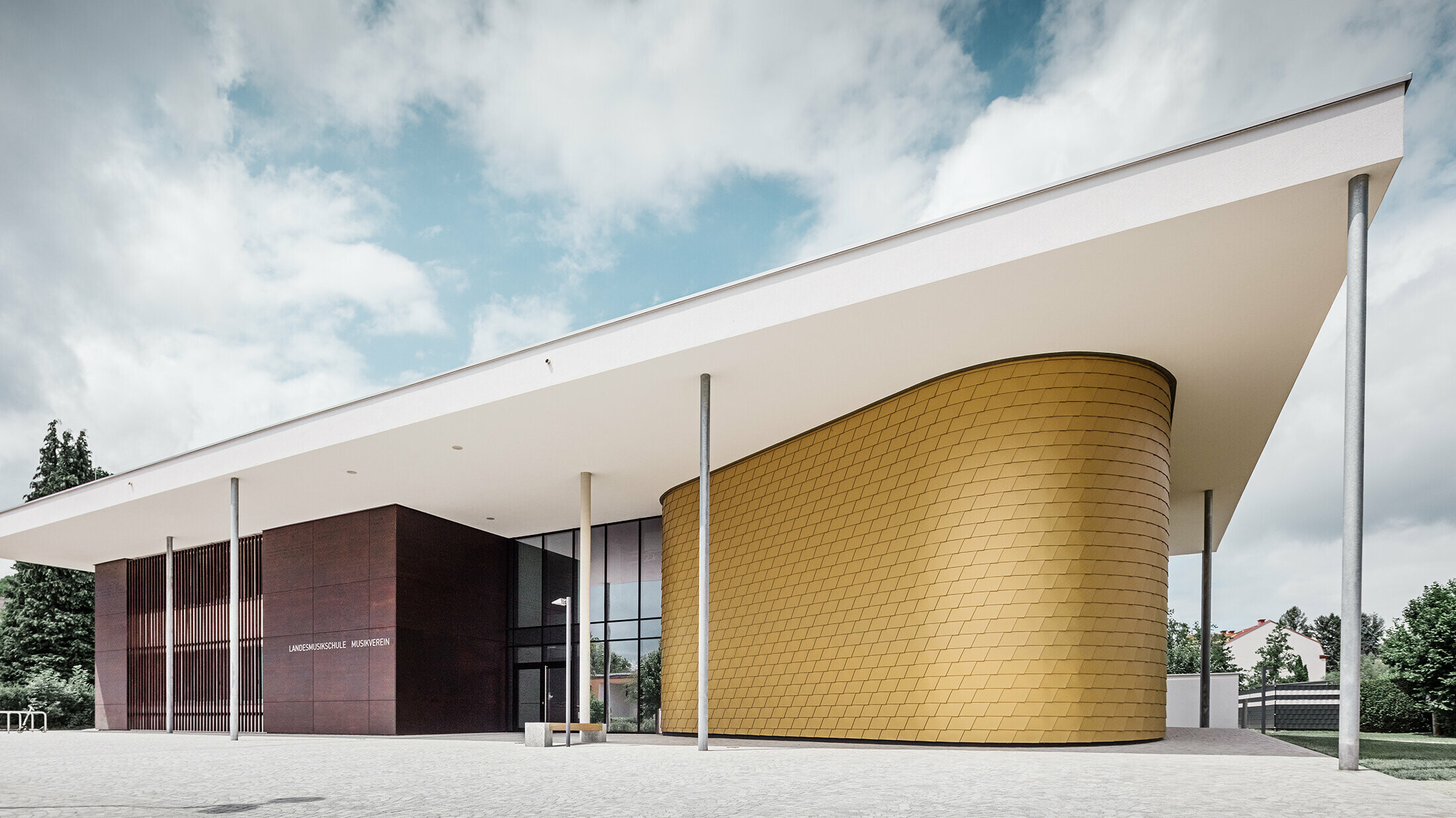 Zlate aluminijaste skodle PREFA krasijo zaobljeno fasado glasbene šole