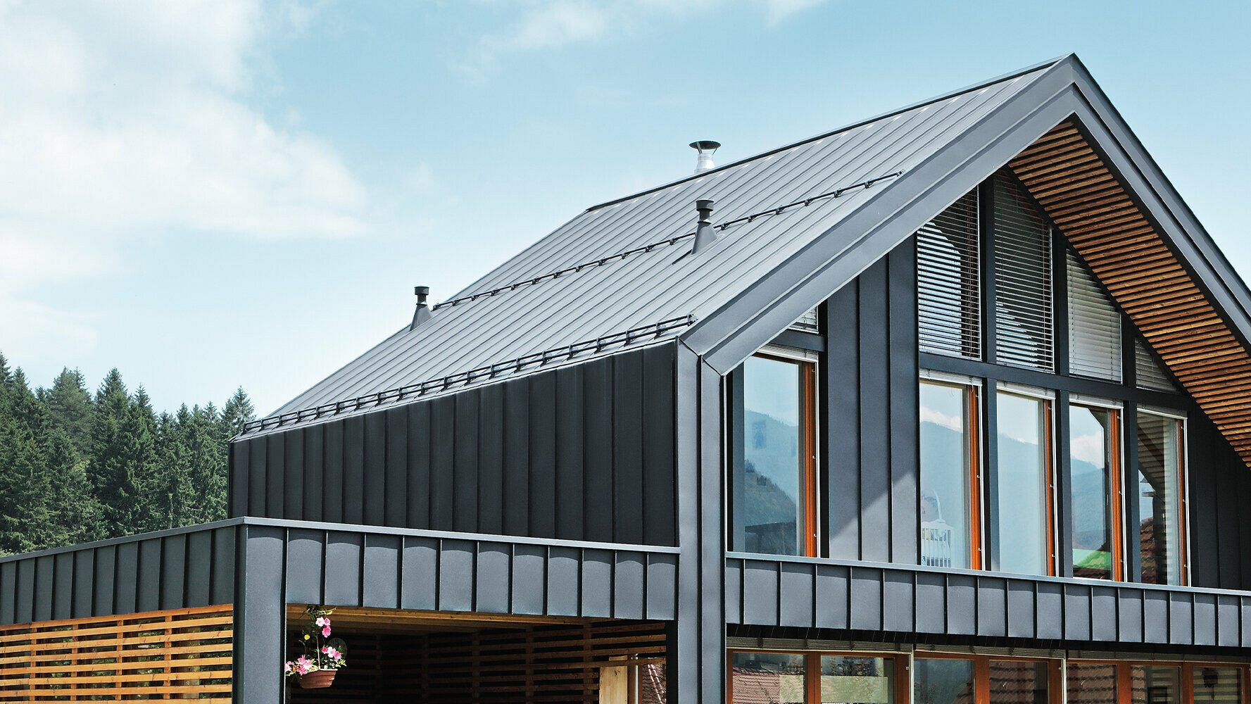 Moderna enodružinska hiša z velikimi okenskimi površinami je oblečena z materialom PREFALZ proizvajalca PREFA. Streha s stoječim zgibom in fasada s kotnim stoječim zgibom tvorita lep ovoj stavbe v antracitni.