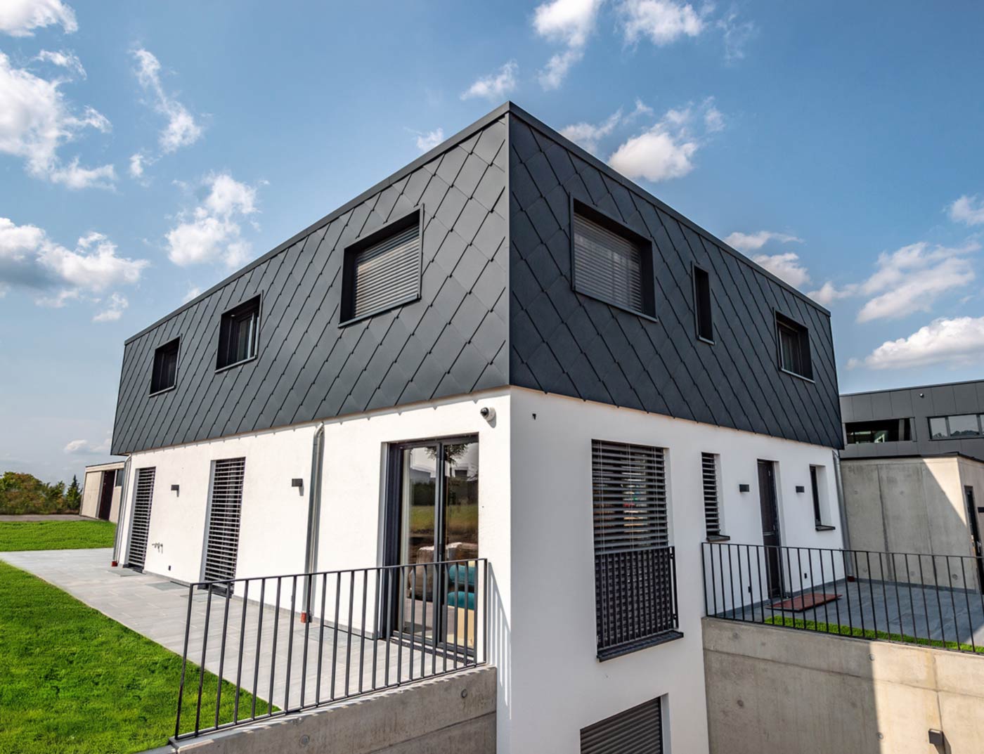 PREFA Wandraute 44 × 44 Anthrazit Referenz Moderner Neubau mit Flachdach - die Fassade des Obergeschoßes ist mit der PREFA Alu-Wandraute 44 × 44 in Anthrazit verkleidet. Der untere Fassadenteil ist weiß verputzt.